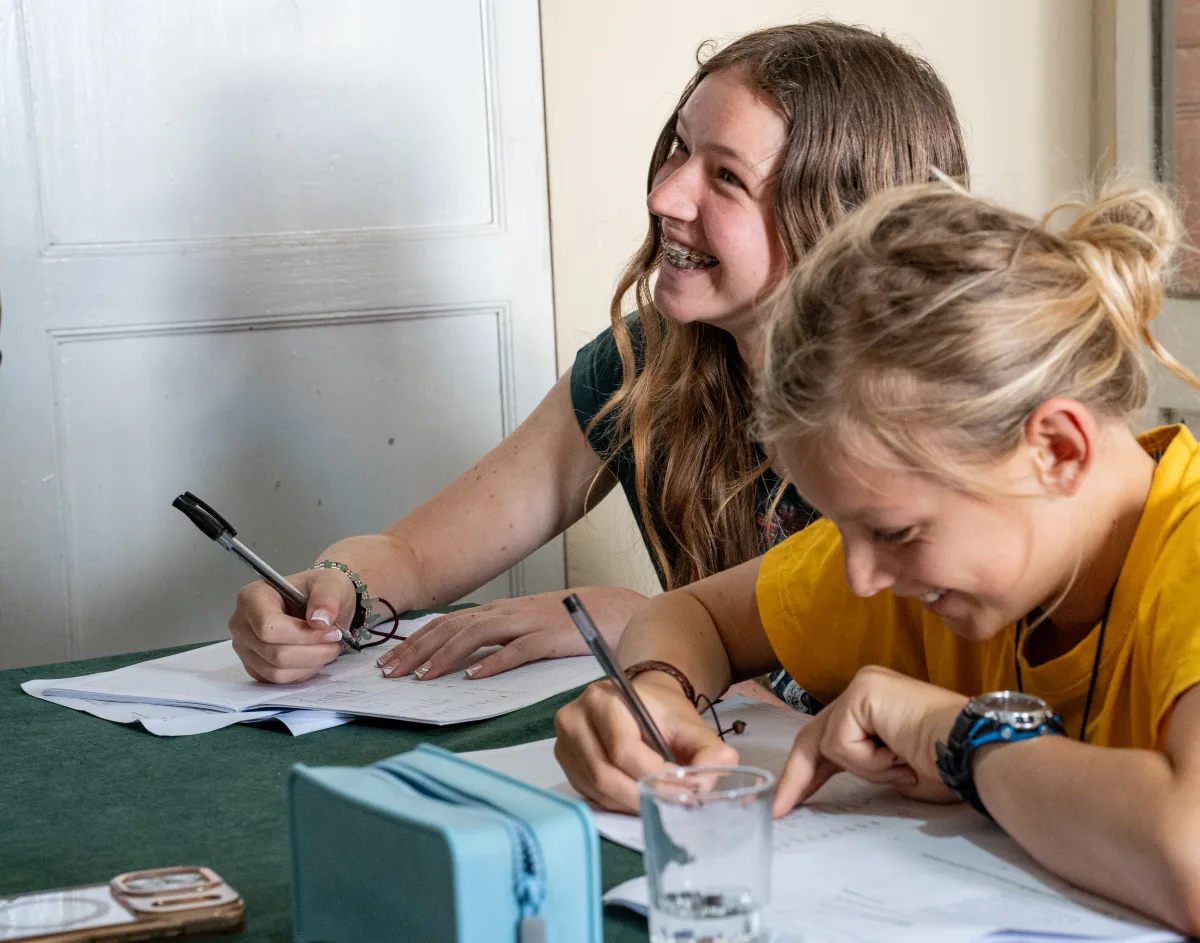 Two students laughing while writing Spanish together